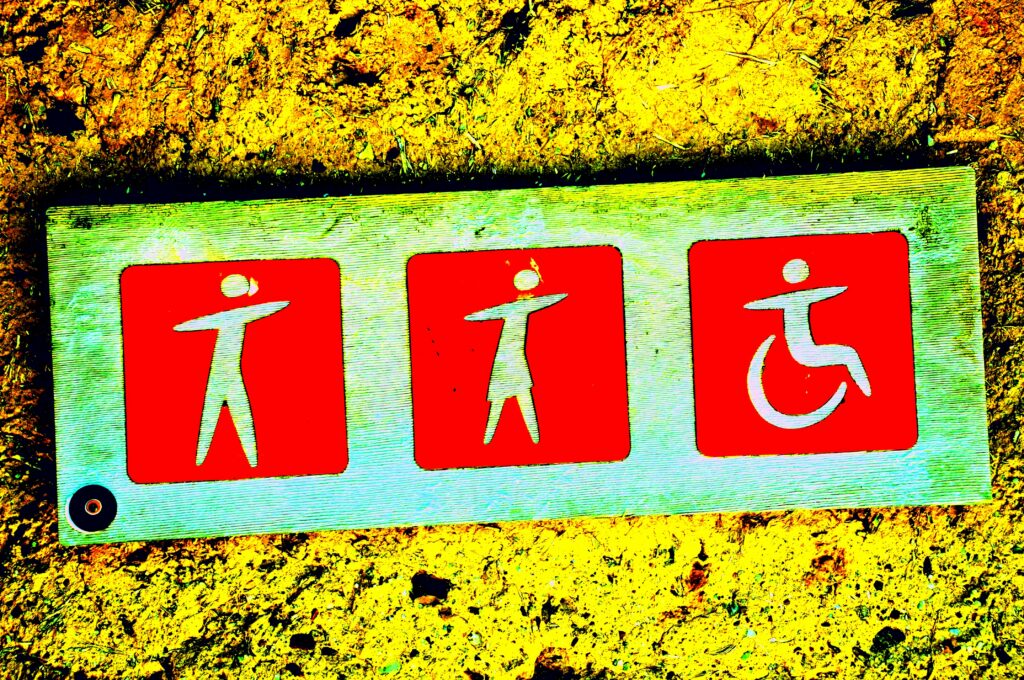 A sign with a stick figure man, woman and wheelchair user, all with arms outstretched on a red background. 