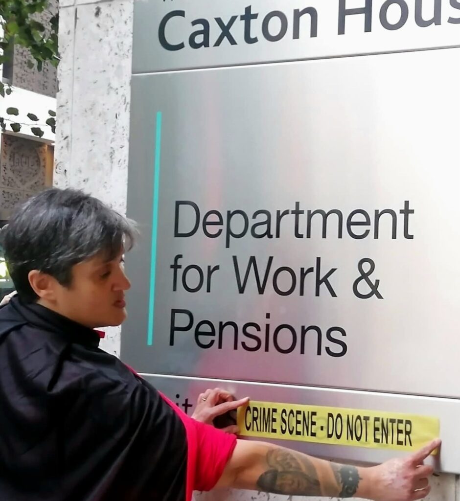 Dolly applies Crime scene tape to the sign outside the Department for work and Pensions.