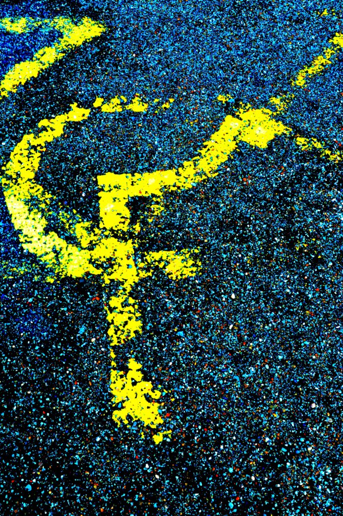 A photo of a an accessible parking bat with a yellow painted logo of a person in a wheelchair on the tarmac.