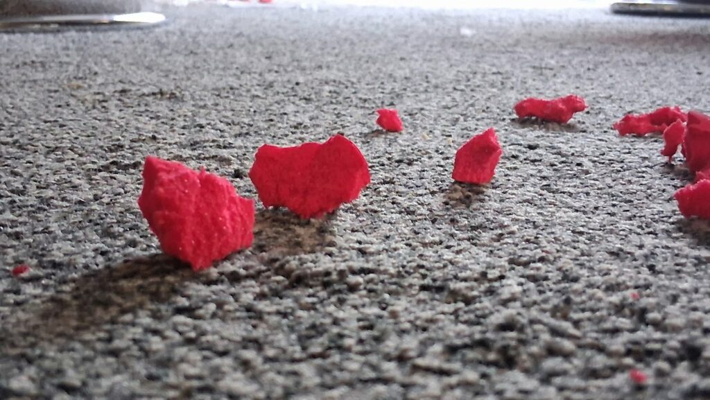 Red bits of foam scattered across a grey carpeted floor.