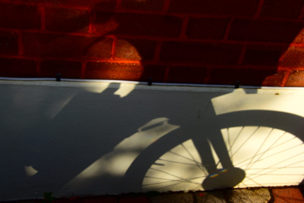 A bicycle casts its shadow over a concrete and red brick wall